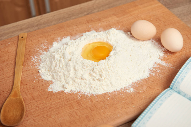 Flour and yolk closeup for baking on a wooden background. Raw food and kitchen utensils. - Foto, Bild