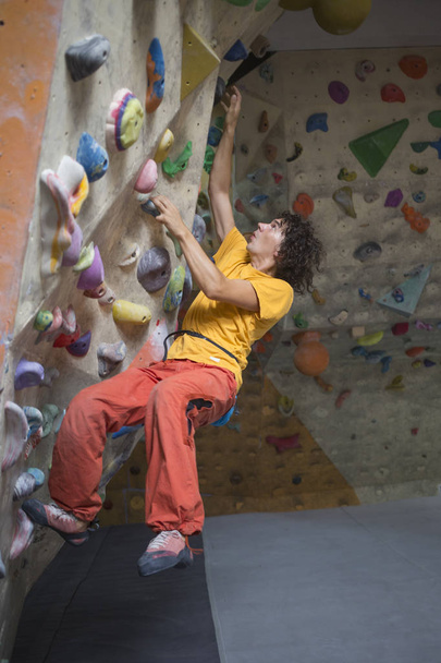 Rock climber bouldering intdoors on climbing wall - Foto, Bild