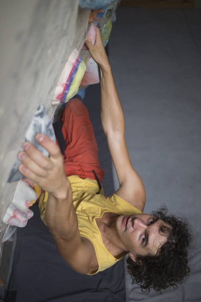 Rock climber bouldering intdoors on climbing wall - Photo, Image
