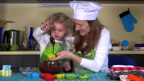 Krásná dcera pomáhá její matka vyplňovat formuláře muffin s těsto těsto - Záběry, video
