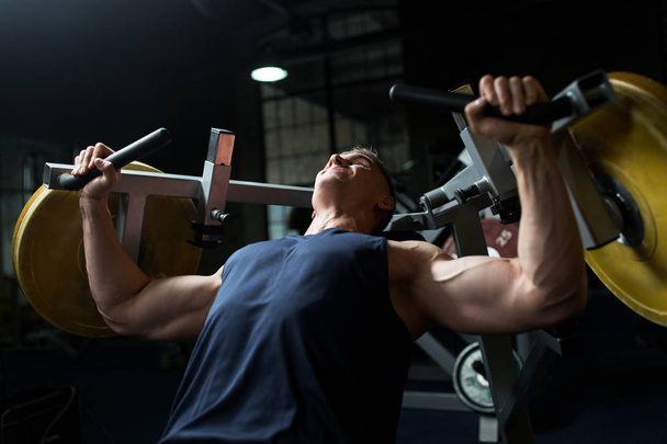 man doing chest press on exercise machine in gym - Foto, Imagen
