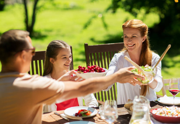 glückliche Familie beim Abendessen oder Sommerfest im Garten - Foto, Bild