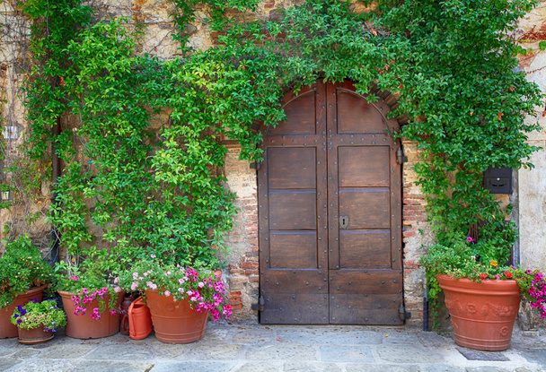 Beautiful old wooden door decorated with flowers, Italy - 写真・画像