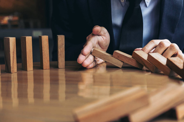 Close up of businessman hand Stopping Falling wooden Dominoes ef - Фото, зображення