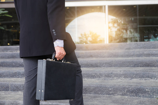 Businessman walking up the stairs and holding a briefcase in han - Foto, imagen