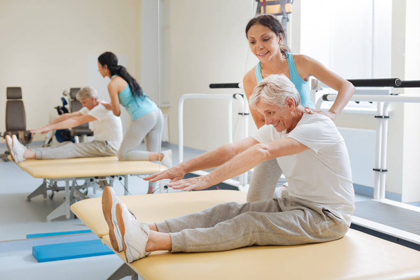 Positive delighted retirement doing stretching exercises - Foto, imagen