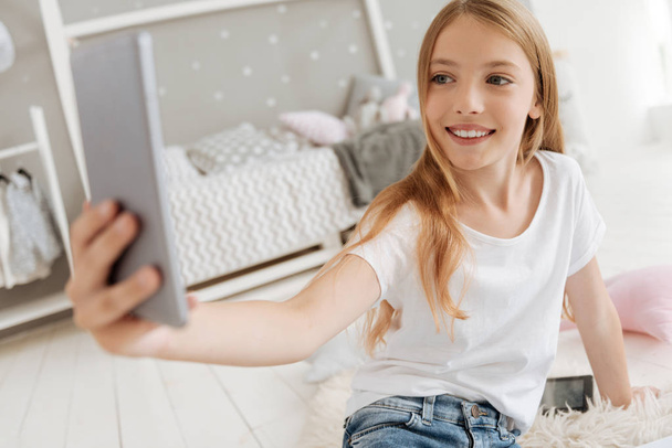 Excited little girl taking selfies in her bedroom - Photo, Image
