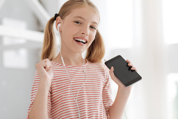 Beaming schoolgirl getting excited with music plying - Foto, Imagen