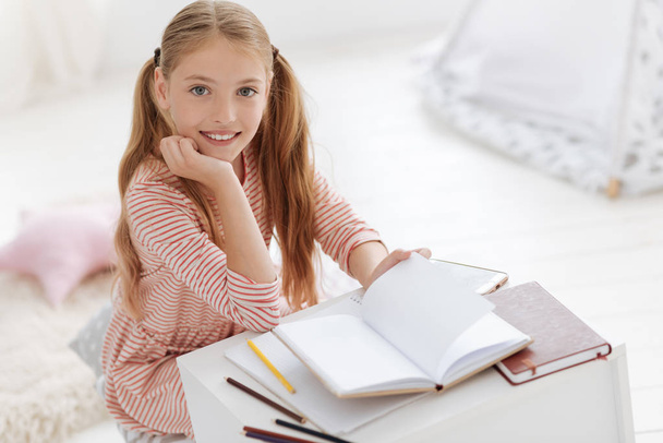 Pretty female youngster smiling into camera while studying - Φωτογραφία, εικόνα