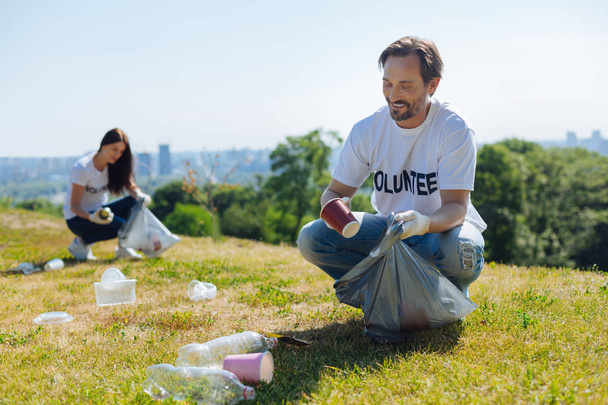 Focused motivated man cleaning local park from litter - Photo, image