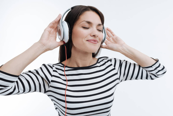 Positive delighted brunette putting hands on headphones - Photo, Image