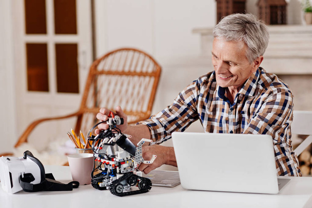 Happy mature man playing with robot - Photo, image