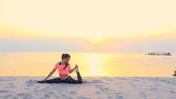 Sağlıklı, genç güzel kadın meditasyon, germe, pratik yoga deniz plajda güneş doğarken, denge ve koordinasyon, derin Kas tonusu için egzersizler yapar - Video, Çekim