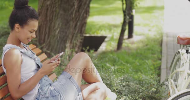 Chica de contenido usando smartphone en el parque
 - Metraje, vídeo