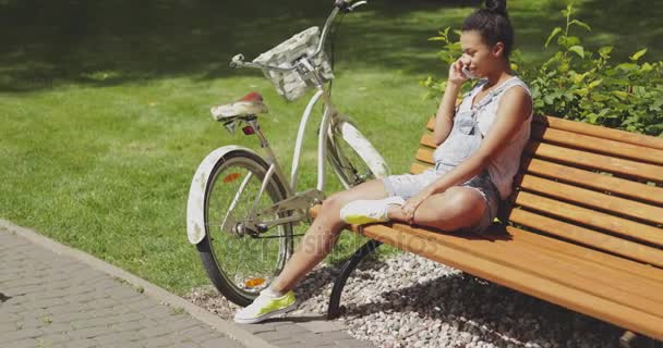 Woman talking phone on bench - Filmati, video