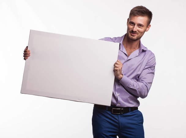 Young glad man showing presentation, pointing on placard - Foto, afbeelding