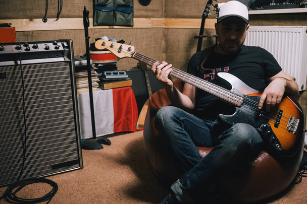 Bass guitarist with guitar in garage studio - Fotó, kép