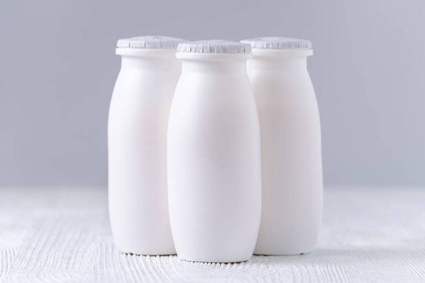 yoghurt drink in plastic flessen op grijze achtergrond - Foto, afbeelding