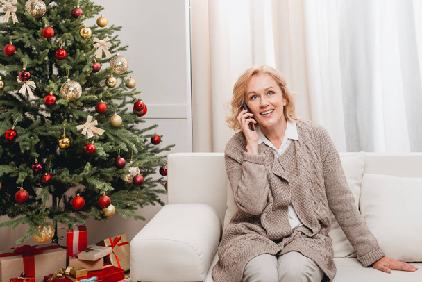 woman talking on smartphone near christmas tree - Zdjęcie, obraz