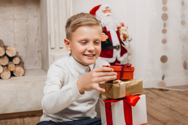 boy making stack of christmas gifts - Фото, изображение