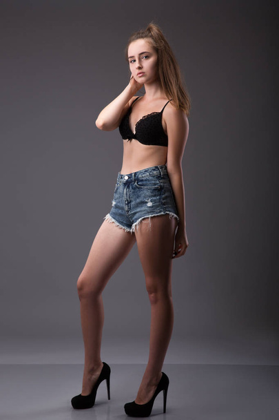 European sexy fashion model with natural brunette hair, long legs, perfect skin posing in studio, wearing black shoes, short andbra, beauty photo, - Photo, Image