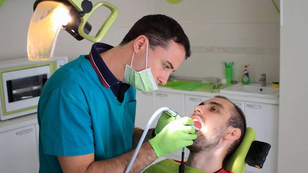 Jeune homme scellant sa dent au cabinet dentaire
 - Photo, image