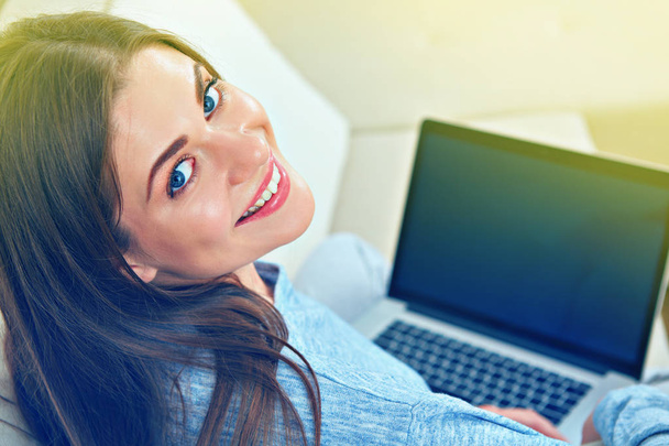 Smiling woman sitting back on sofa with laptop - Foto, afbeelding