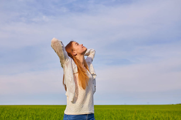 Girl with open arms on a green wheat field - Photo, Image