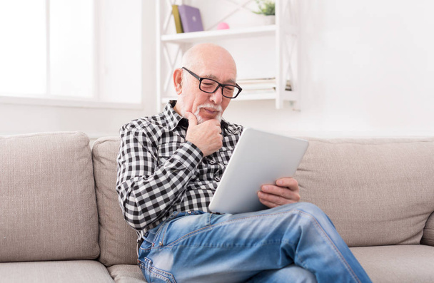 Senior man reading news on digital tablet - Photo, Image