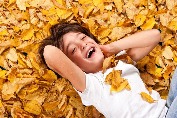 6 years kid laughing, lying on autumn leaves - Фото, изображение
