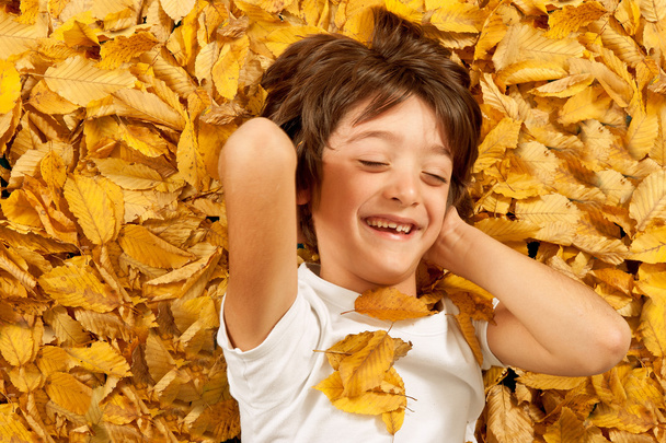 6 years kid laughing, lying on autumn leaves - Fotoğraf, Görsel