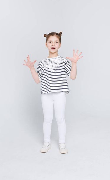 Έκπληκτοι το χαριτωμένο μικρό κορίτσι δείχνει τις παλάμες σε φόντο λευκό στούντιο - Φωτογραφία, εικόνα