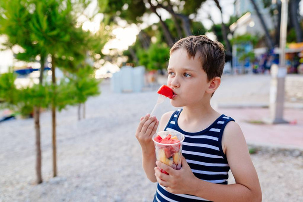Criança comendo frutas fatiadas
 - Foto, Imagem
