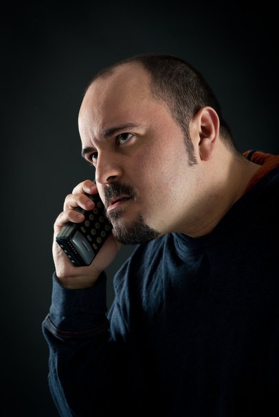 Angry man talking at the phone against black background - Фото, зображення