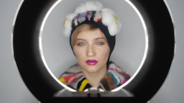 Close-up rosto de modelo de moda em um chapéu com maquiagem profissional em estúdio. Menina com lábios cor de rosa
. - Filmagem, Vídeo