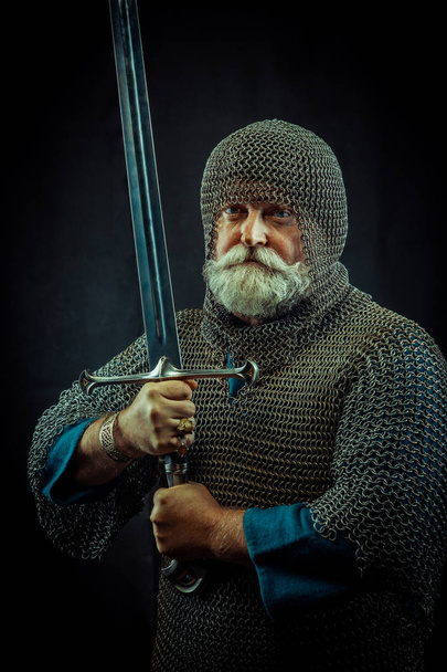 Koyu arka plan üzerinde kılıçla güçlü sakallı knight - Fotoğraf, Görsel