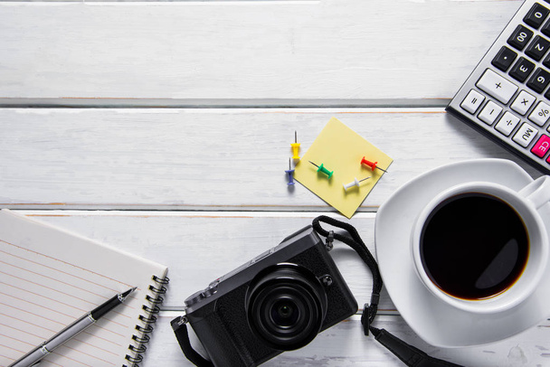 Bild von oben mit Kaffee, Kamera und Notizbuch auf weißem Holz - Foto, Bild