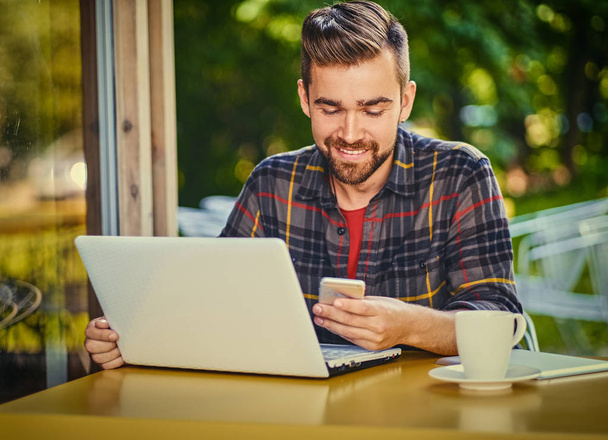 Όμορφος άνδρας χρησιμοποιώντας ένα φορητό υπολογιστή σε ένα καφέ - Φωτογραφία, εικόνα
