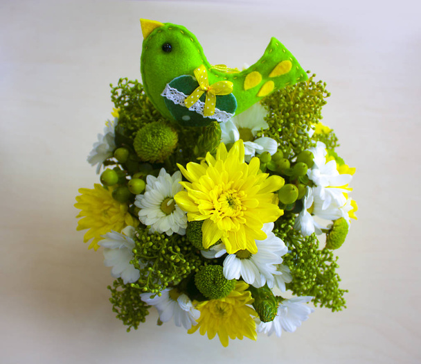 Strauß schöner heller Blumen in einem gelb-grünen Rangeon auf dem Tisch - Foto, Bild