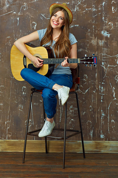 Smiling young woman playing on acoustic guitar. - 写真・画像