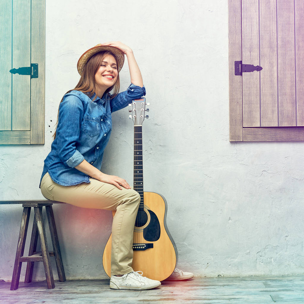 Womann sitting on bench with guitar. - Фото, изображение