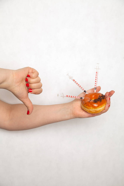 Ближе к врачу женщина делает инъекции с помощью шприца от диабета в пончик
 - Фото, изображение