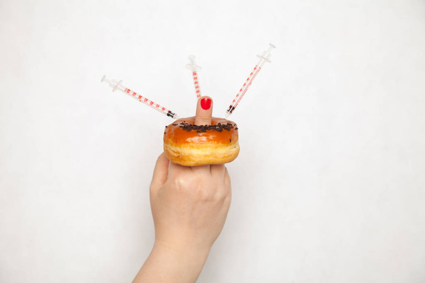 Close-up op arts vrouw maken injectie met behulp van diabetes spuit in donut - Foto, afbeelding