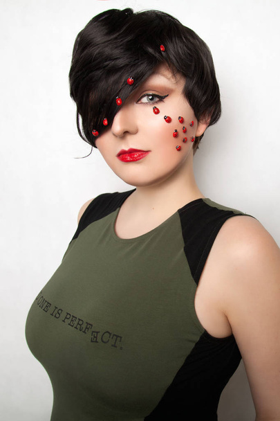 pretty brunette pin up woman wearing green dress with ladybugs on face on white background isolated - Photo, Image