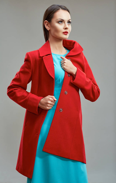 Fashion model dressed in red coat and light blue dress posing i - Foto, afbeelding