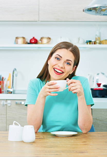 vrouw zitten in de keuken met koffiekopje  - Foto, afbeelding