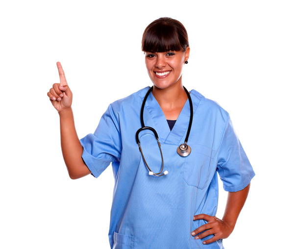 Charming young nurse looking at you pointing up - Foto, imagen