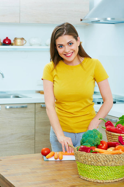 woman in kitchen cooking vegetables. smiling young woman  - Фото, изображение
