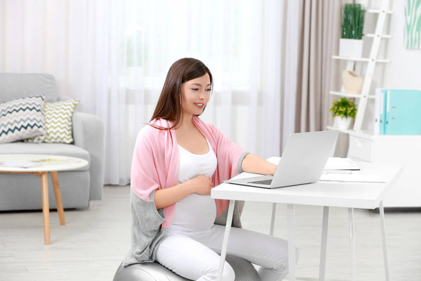 Beautiful young pregnant woman working at home - 写真・画像