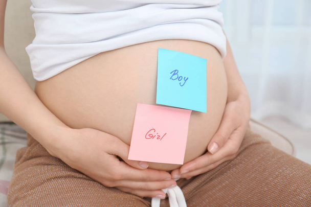 Pregnant woman with paper stickers on tummy, closeup. Concept of choosing baby name - Foto, Imagen